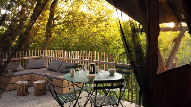 An outdoor seating area with a round table, chairs, and a sofa. - Village Huttopia Sud Ardèche (Vagnas)