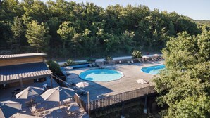 A pool area with two pools, lounge chairs, umbrellas, and a wooden deck. - Village Huttopia Sud Ardèche (Vagnas)