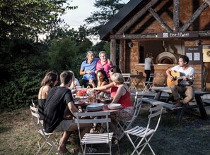 An outdoor dining area with a rustic wooden building labeled "Four d'Pizza" in the background. - Village Huttopia Sud Ardèche (Vagnas)