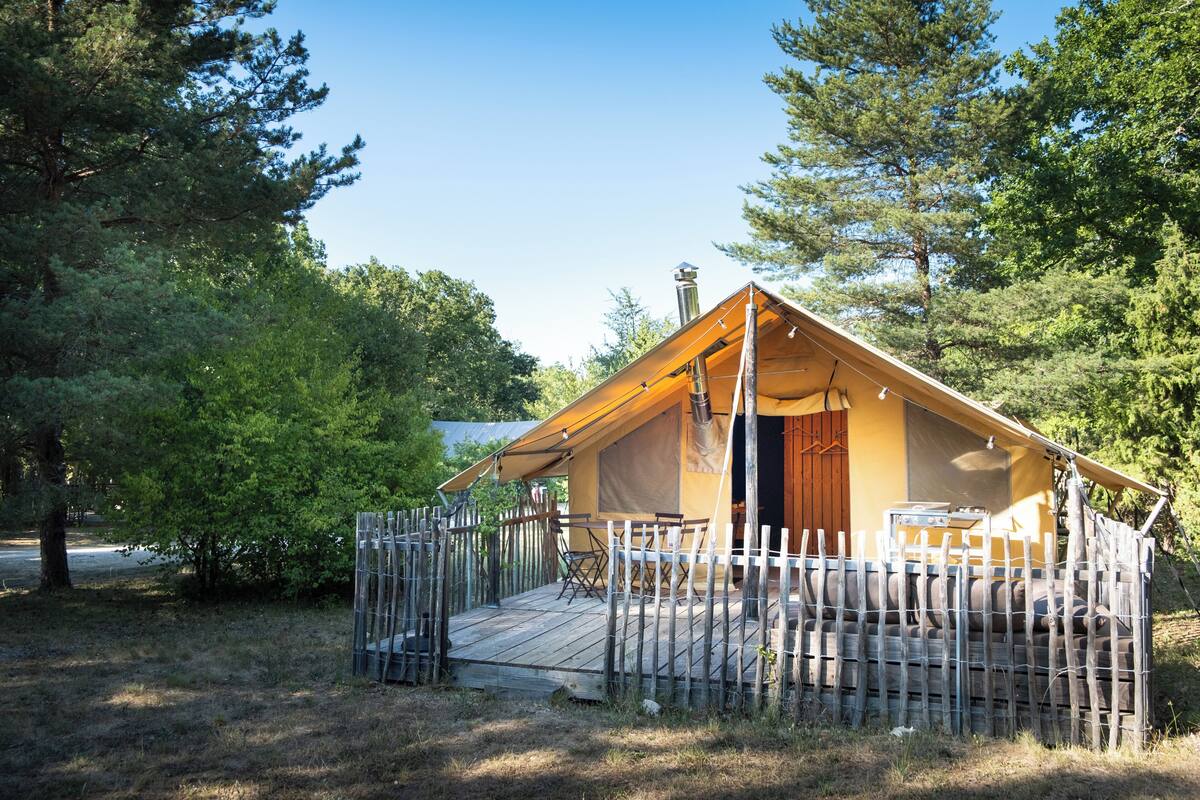 A single-story tent with a wooden deck and a covered outdoor seating area.
