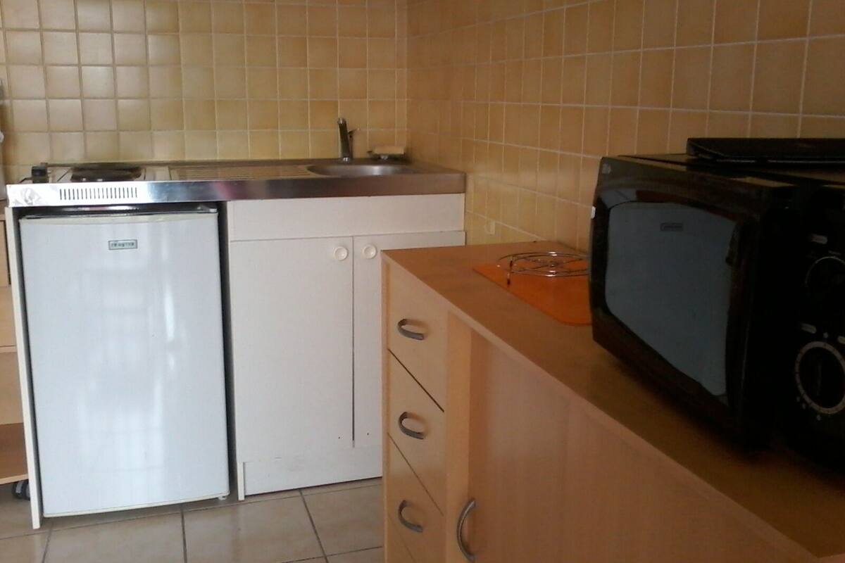 Eine kleine Küche mit einem Kühlschrank, einer Mikrowelle und einem Spülbecken.