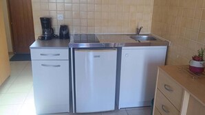 A compact kitchen with a refrigerator, a coffee maker, and a sink.