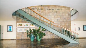 A curved staircase with a metal railing, leading to an upper level. The wall behind the staircase features a tiled design with the text "EKFAI MARINA". - Charming Ilikai Marina Studio, Great Location In Waikiki! (Honolulu)