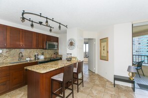 Enjoy cooking in this well-equipped kitchen with a central island, stainless steel sink, and modern lighting.