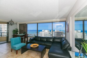 Relax in this stylish living room with a sofa, armchair, and coffee table, offering a panoramic view of the coastal city and ocean.