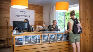 Una recepción con un cartel que dice "Bienvenue HUTTOPIA - LE MOULIN" y una exhibición de postales.