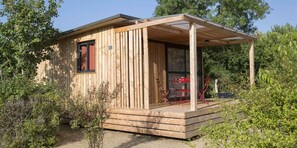 Une petite cabane en bois avec un porche abrité et une seule fenêtre.