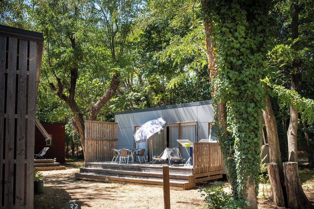 A small cabin with a deck, outdoor seating, and a covered area.