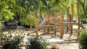 Un parque infantil con estructuras de madera, un tobogán y un banco.