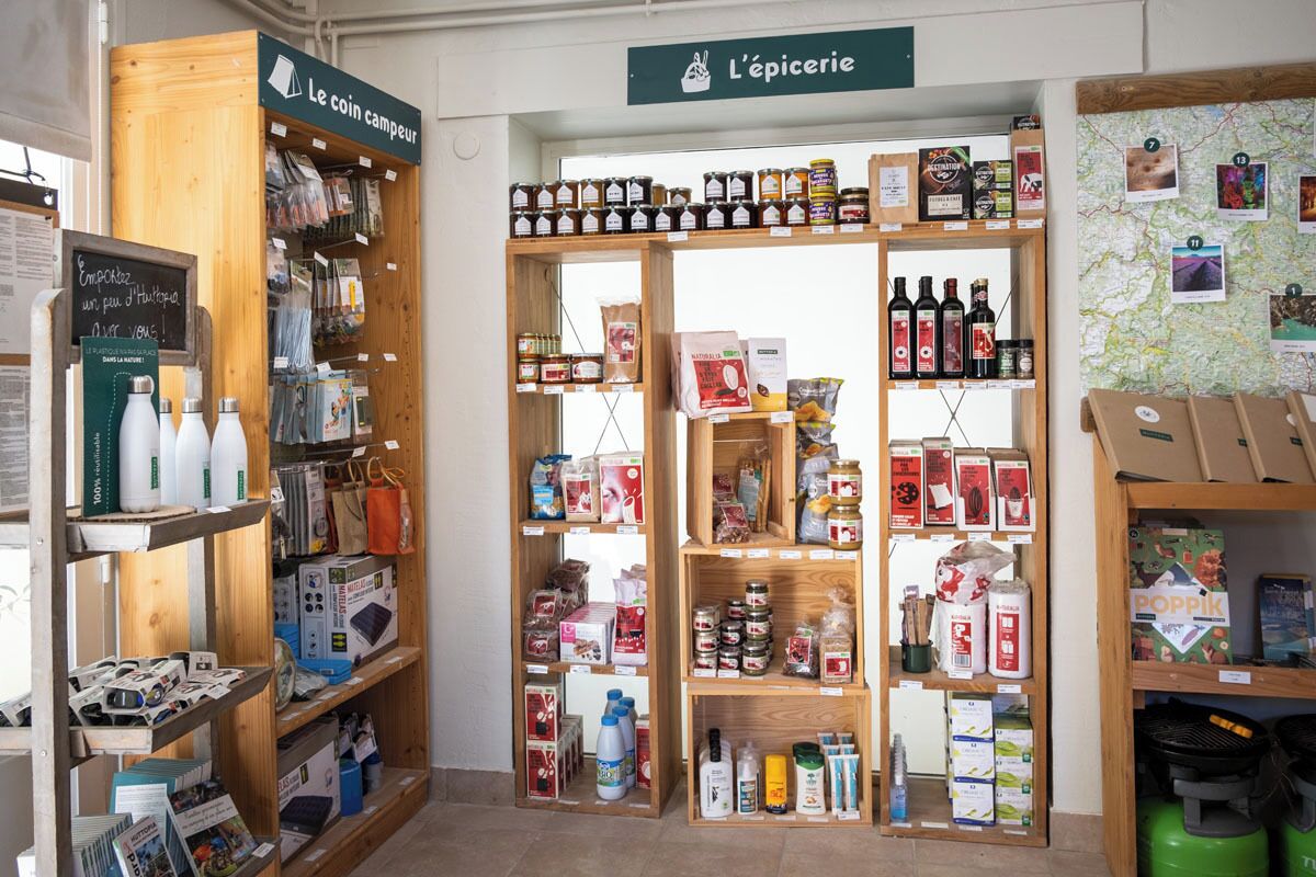 En butik med hyllor av trä, fyllda med olika produkter, inklusive burkar, flaskor och förpackade varor.