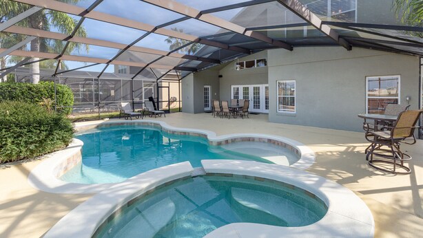 An outdoor swimming pool with a covered patio area, including lounge chairs and a table.
