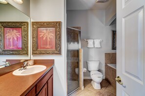 Et badeværelse med vask, to billeder i rammer, toilet, bruser og badekar.