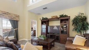 A living room with a brown leather sofa, a wooden coffee table, and a television.