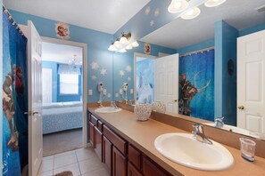 Ein Badezimmer mit zwei Waschbecken, einem Spiegel und einer Duschvorhang mit Frozen-Motiv.