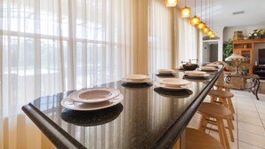 Een moderne keuken met een groot eiland, houten krukken en hanglampen.