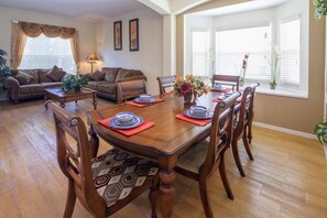Un coin repas avec une table en bois dressée pour six personnes, entourée de six chaises.