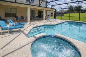 Piscina com espreguiçadeiras e hidromassagem, em volta de um espaço coberto com terraço.