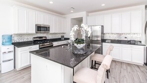 A modern kitchen with white cabinets, a granite countertop, stainless steel appliances, and a water dispenser. - BUTTERFLY Lounge w/2 Masters - 12 min f/the Strip (Las Vegas)