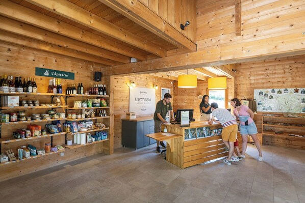 Un interior rústico de madera con estantes llenos de bebidas y aperitivos en botella, un mostrador de recepción y un mapa en la pared.