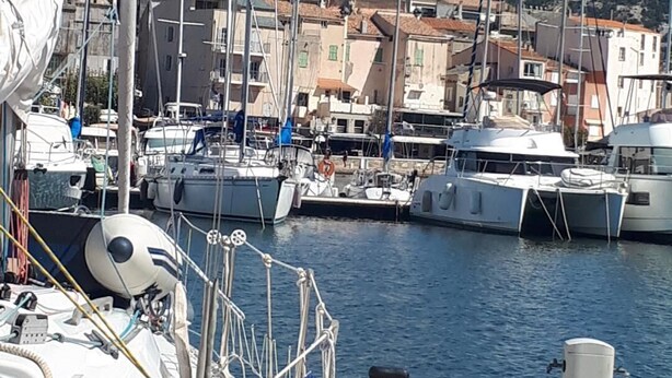 A marina with boats docked, a clear sky, and buildings in the background. - APARTMENT 4/6 PERS (Oletta)