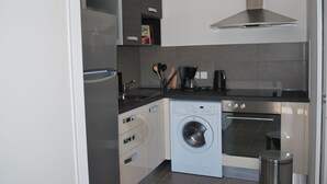 A compact kitchen with a washing machine, oven, and a coffee maker. - APARTMENT 4/6 PERS (Oletta)