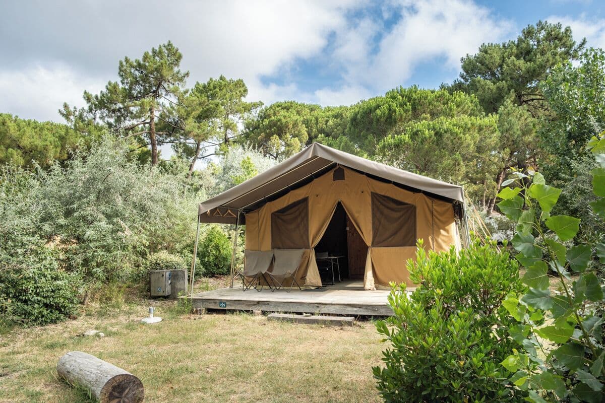 A single-story tent with a flat roof, a front porch, and a small table and chair set outside.