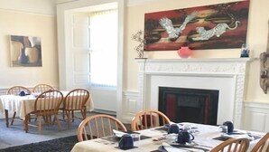 Un comedor con sillas y mesas de madera, una chimenea y un cuadro en la pared.