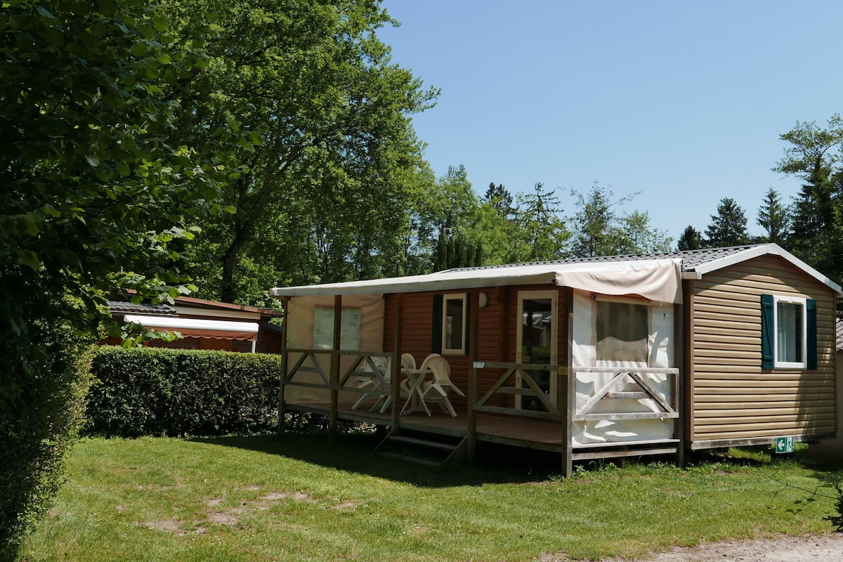 Une maison mobile dotée d’un porche, d’une petite terrasse et d’un espace extérieur couvert.