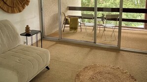 Un salon moderne doté d’une grande porte-fenêtre coulissante donnant sur une terrasse extérieure.