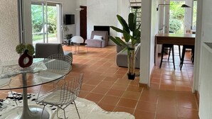 Un vaste espace de vie comprenant une table basse en verre, un tapis en cuir blanc et une table à manger avec des chaises.