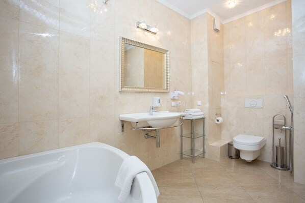 A modern bathroom with a bathtub, a sink, a toilet, and a shower.