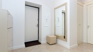 A hallway with a door, a mirror, a small bench, and a wall-mounted phone. - MinskLux Apartments Deluxe 1 bedroom on Nezavisimosti ave. 13 (Minsk)