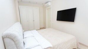 A bedroom with a bed, a white wardrobe, and a mounted TV. - MinskLux Apartments Deluxe 1 bedroom on Nezavisimosti ave. 13 (Minsk)