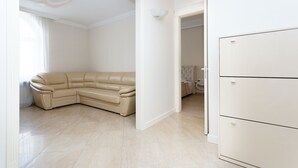 A room with a beige sectional sofa, a white wardrobe, and a door leading to another room. - MinskLux Apartments Deluxe 1 bedroom on Nezavisimosti ave. 13 (Minsk)