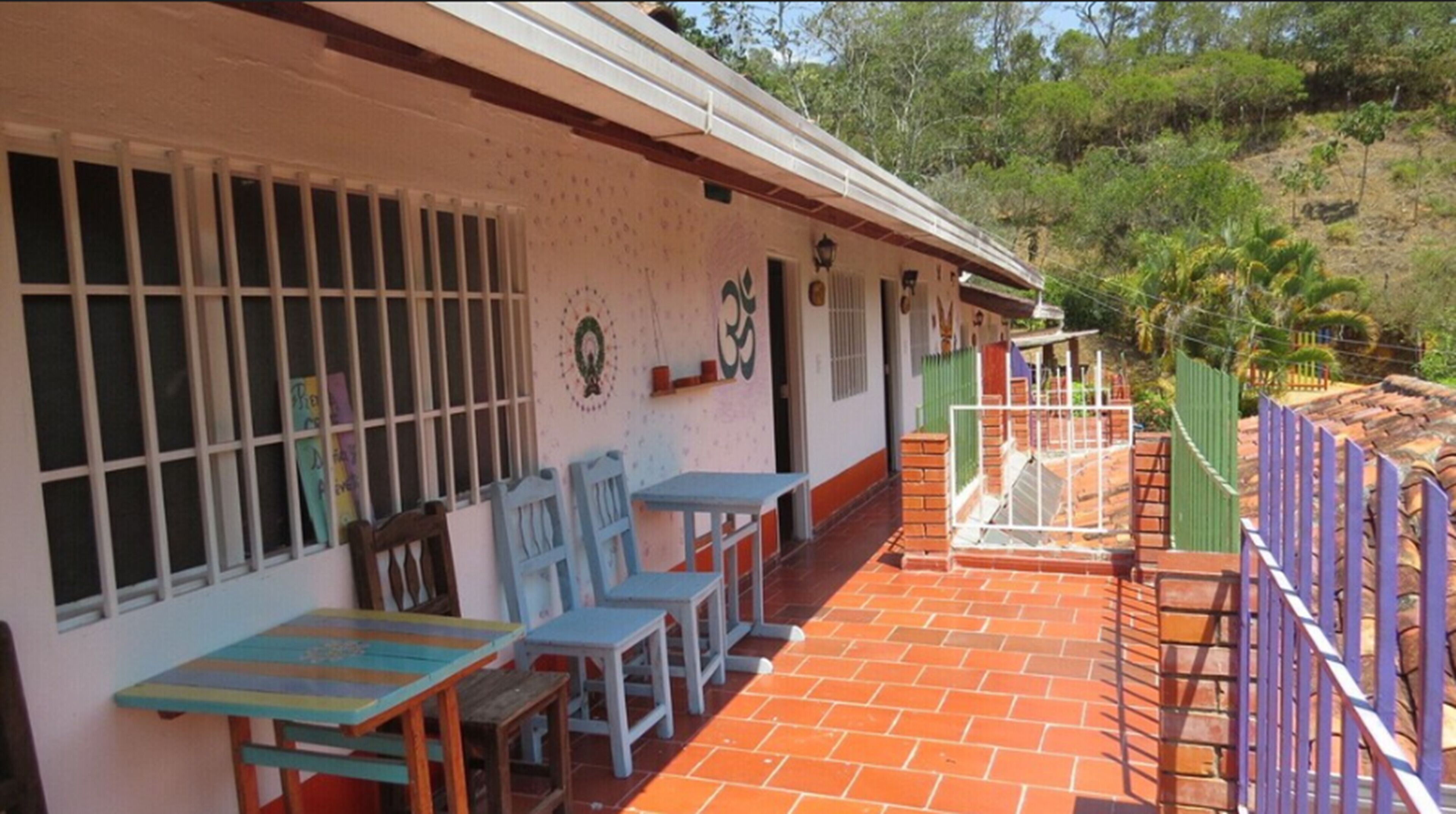 A building with a tiled patio, outdoor seating, and a fenced area.