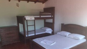 Une chambre avec un lit superposé, une commode en bois et un sol carrelé.