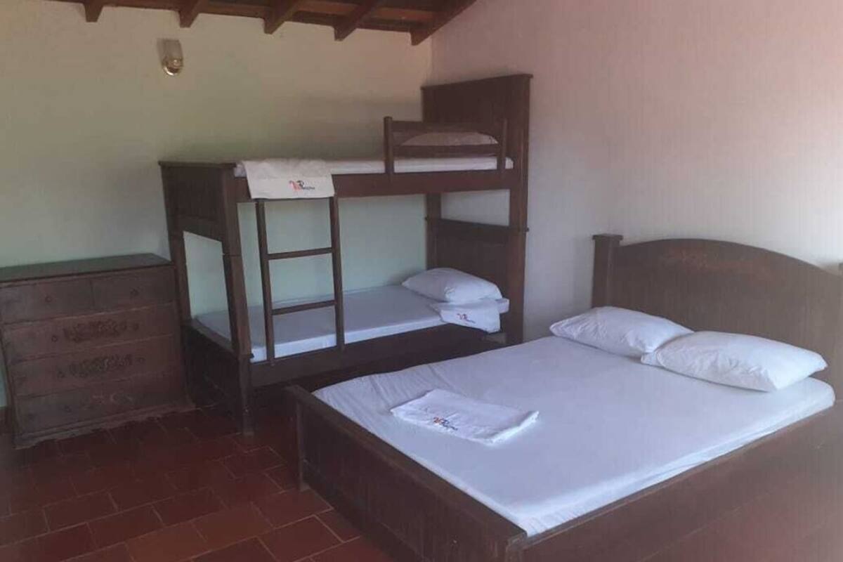 Une chambre avec un lit superposé, une commode en bois et un sol carrelé.