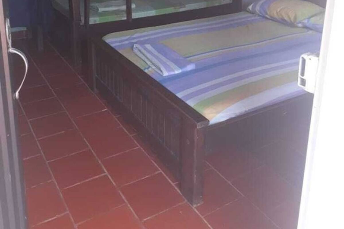 Une chambre de dortoir avec des lits superposés, un petit bureau et un sol carrelé.