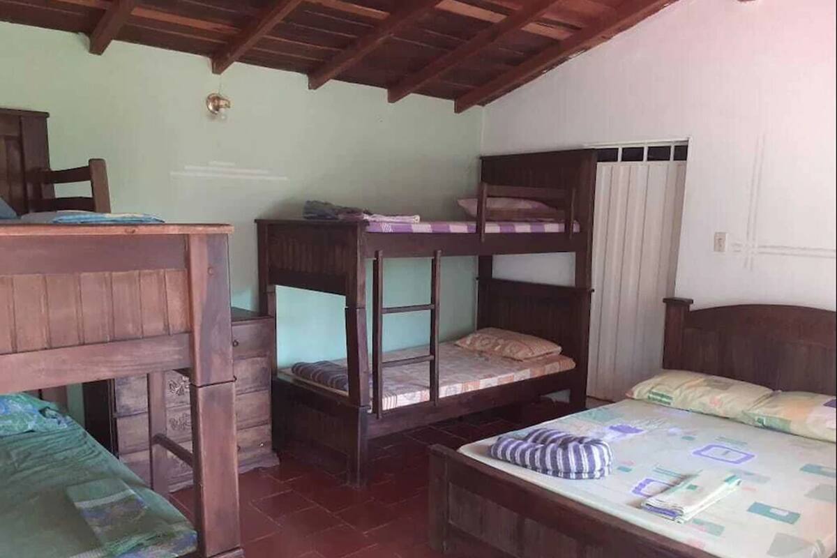 Une chambre avec des lits superposés, un bureau en bois et un lit recouvert d’une courtepointe à motifs.