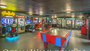 A room with a pool table, various arcade games, and a Batman-themed machine.