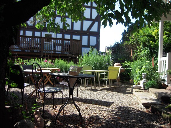 An outdoor patio area with a table and chairs, surrounded by gravel and greenery.
