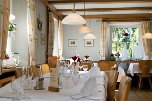 A dining area with tables set for a meal, chairs, hanging pendant lights, and framed pictures on the walls. - Gasthaus zur Blume (Efringen-Kirchen)
