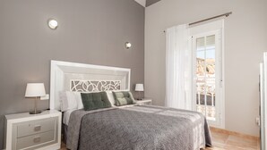Un dormitorio con una cama grande, dos mesitas de noche y una puerta que ofrece vistas al exterior.