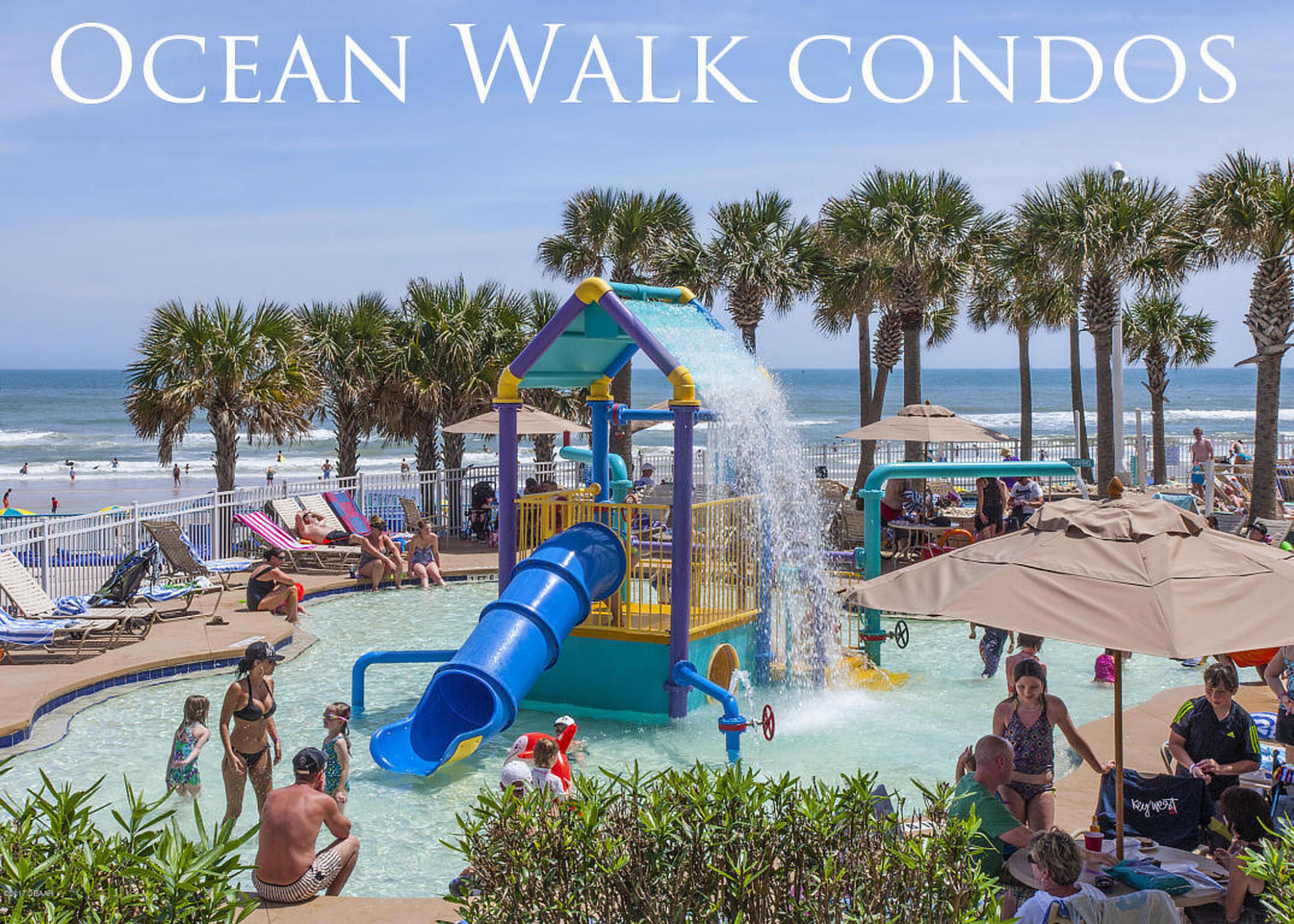 A water park with slides and play structures, surrounded by palm trees and beach chairs.