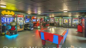 Una habitación con mesa de billar, varios juegos de arcade y una máquina con temática de Batman.