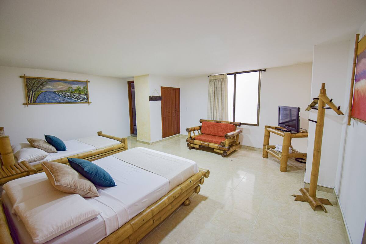 Une chambre d’hôtel avec deux lits, une télévision, un tableau et une fenêtre avec des rideaux.