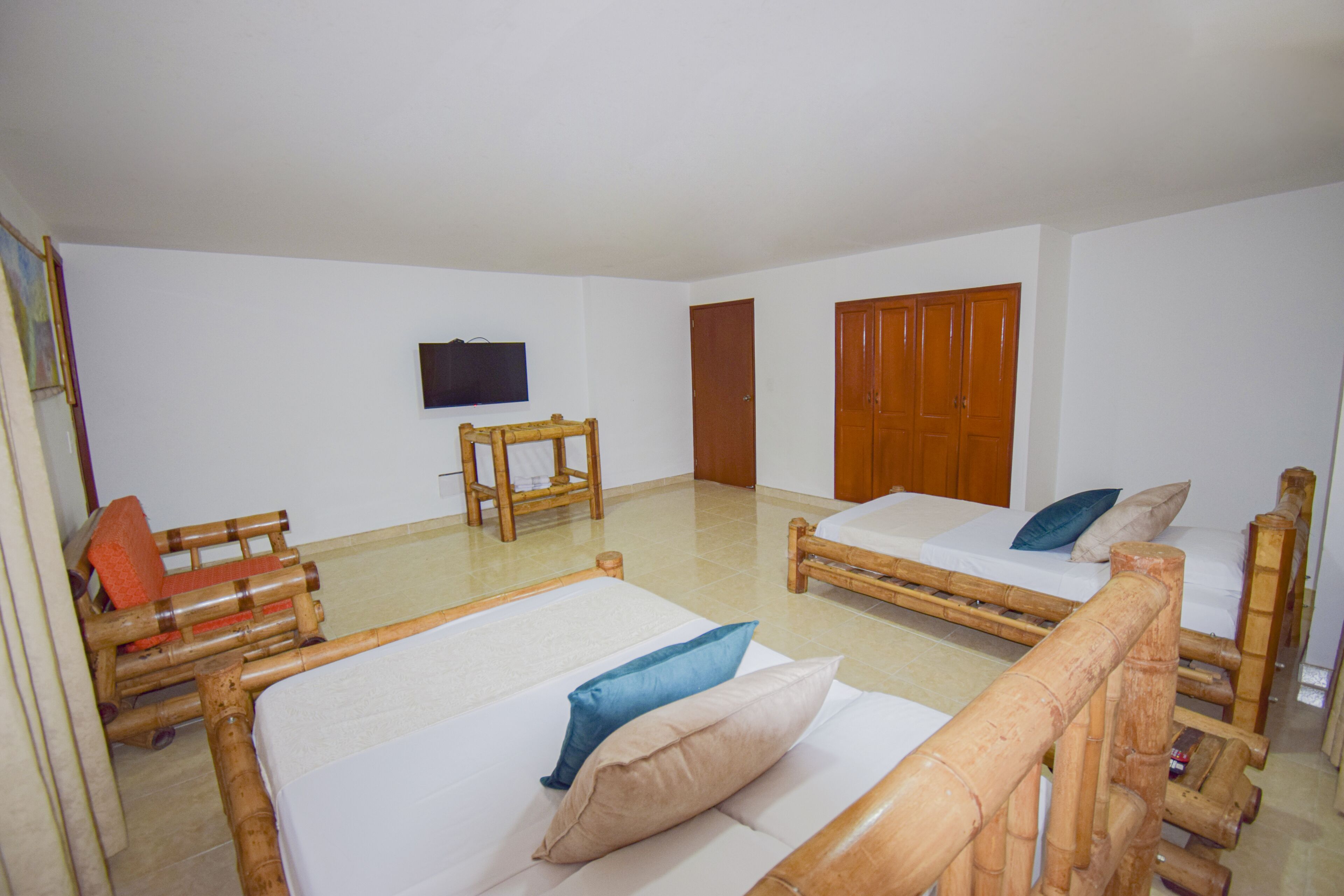 Une chambre avec deux lits simples, une chaise en bois, un téléviseur et une armoire.