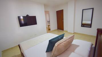 A bedroom with a bed, a TV mounted on the wall, and a mirror.