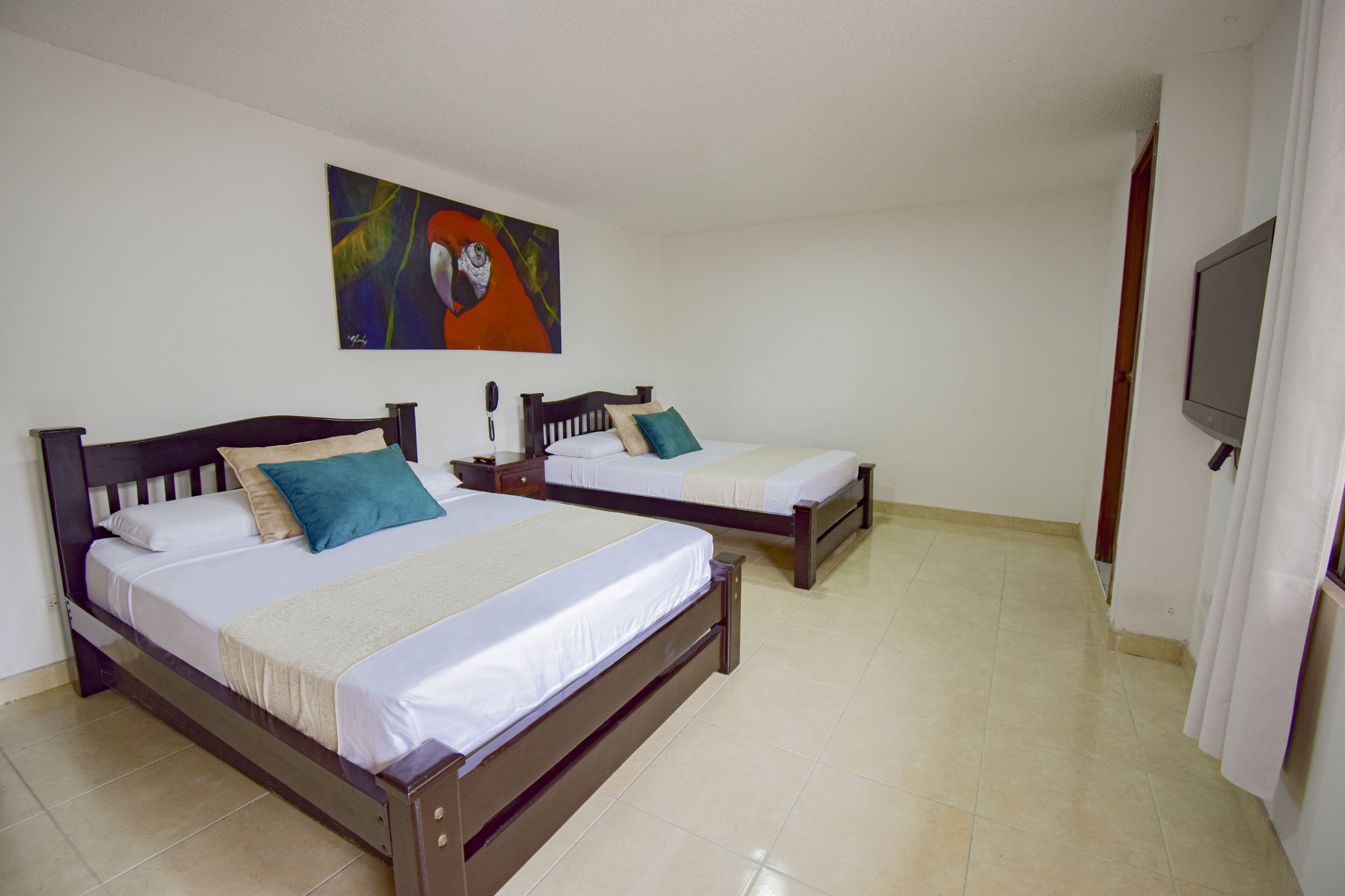 A hotel room with two wooden beds, white bedding, and a painting on the wall.