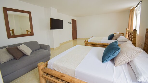 Ein Hotelzimmer mit einem großen Bett, einer Couch, einem Fernseher und einem Spiegel.